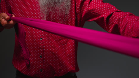 Close-Up-Low-Key-Studio-Lighting-Shot-Of-Senior-Sikh-Man-Folding-Fabric-For-Turban-Against-Plain-Dark-Background-Shot-In-Real-Time-1